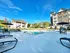 Inviting outdoor area featuring a modern pool with poolside loungers and stylish outdoor seating, surrounded by well-maintained landscaping and contemporary apartment buildings under a clear blue sky.