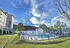 Stunning apartment complex with a refreshing outdoor pool surrounded by lush greenery and a picturesque sky, perfect for relaxation and leisure.