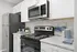 Modern kitchen with sleek stainless steel appliances, elegant white cabinetry, and chic countertop decor.