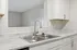 Modern kitchen with sleek marble countertops, dual stainless steel sink, and elegant white cabinetry.