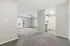 Bright and spacious apartment interior featuring a modern open-concept living area with fresh gray carpeting, a ceiling fan for comfort, and a cozy kitchen with contemporary cabinetry.