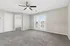 Sunlit living area with plush carpeting, modern ceiling fan, and patio access through stylish double doors.