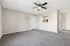 Bright, open living room with plush carpet, ceiling fan, and modern kitchen view.