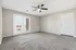 Bright living room featuring plush carpeting, modern ceiling fan, and elegant French doors opening to a scenic view.