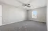 Bright and airy bedroom with plush gray carpet, neutral walls, and a ceiling fan, offering a cozy retreat.