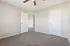 Bright, neutral-toned bedroom with plush carpeting and ceiling fan, offering a cozy and inviting space.