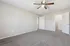 Bright and airy bedroom with soft carpeting, ceiling fan, and two open doors leading to a closet and hallway.