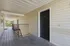 Welcoming apartment entryway with modern black door and wooden walkway, offering a bright, airy atmosphere.