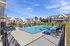 Inviting apartment complex with a sparkling swimming pool and comfortable lounge chairs, surrounded by charming brick buildings and lush green lawns.
