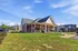 Charming red brick apartment complex with modern design, expansive green lawns, and ample parking, bathed in bright sunlight.