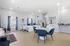 Modern, sunlit office space featuring sleek blue chairs, white desks, and elegant decor, perfect for professional interactions.