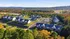 Inviting aerial view of a modern apartment community nestled in lush greenery with scenic landscapes, featuring spacious building layouts and ample parking.