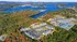 Stunning aerial view of a lakeside apartment complex surrounded by lush greenery and vibrant autumn foliage, offering serene living with picturesque water views.