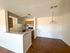 Bright and open apartment kitchen with modern cabinets and adjacent dining area with wooden flooring.