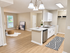 Inviting open-concept apartment kitchen with modern white cabinetry, stylish granite countertops, and cozy living area with wooden floors and natural light.