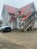 Charming multi-story house with red metal roof, wooden staircase, and ample parking space.