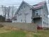 Charming two-story home with modern gray siding, red roof accents, and a spacious fenced yard, perfect for family living.