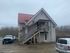 Charming two-story residence with a red metal roof, spacious balcony, and ample parking in rustic surroundings.