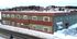 Charming multi-use building in a winter setting, featuring classic brick and green facade with ample large windows, perfect for commercial or residential use at Village Square.