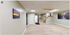 Bright and inviting hallway with stylish wooden flooring, modern ceiling panels, and vibrant landscape artwork.