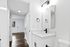 Elegant bathroom with sleek black fixtures and a modern vanity, leading into a bright hallway with rich wooden floors.