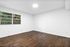 Bright and airy room with elegant hardwood flooring, large window showcasing lush greenery.