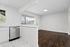 Chic open-plan kitchen and living area with sleek stainless steel appliances and large windows offering natural light, creating a bright and airy space.