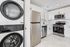 Sleek modern kitchen featuring stainless steel appliances, marble flooring, and an in-unit washer dryer.