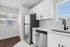 Bright and modern kitchen featuring sleek stainless steel appliances, elegant white cabinetry, and large windows inviting natural light.