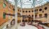 Captivating museum interior featuring impressive dinosaur skeletons under a stunning vaulted glass ceiling with brick walls and circular windows.