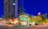 Vibrant urban scene showcasing a modern high-rise next to a well-lit Publix supermarket, set against a brilliant evening sky.