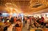 Vibrant restaurant with modern wooden ceiling and elegant lighting, buzzing with people enjoying dining and socializing.