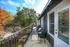 Charming apartment balcony with cozy seating, surrounded by lush trees and vibrant autumn colors, ideal for relaxing afternoons.