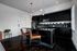 Modern kitchen with sleek black cabinets, stylish pendant lighting, and a chic hexagonal backsplash, featuring a spacious island with leather bar stools.