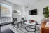 Bright and modern living room with sleek decor, featuring a leather sofa, elegant armchairs, and a stylish coffee table. Large windows provide ample natural light, enhancing the cozy atmosphere.