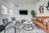 Modern living room featuring a sleek leather sofa, stylish artwork, and cozy seating area with natural light from multiple large windows.