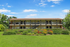 Charming two-story apartment building with lush landscaping and vibrant flowers under a clear blue sky.