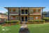Charming brick apartment building with landscaped gardens and inviting front porches, perfect for relaxed living.