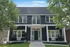 Elegant two-story building with a modern navy exterior, large windows, and inviting porch swing surrounded by lush greenery.