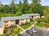 Charming apartment complex surrounded by lush greenery, featuring spacious parking and inviting pathways, perfect for serene living.