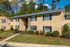Charming brick apartment complex with well-maintained landscaping, featuring lush greenery and a welcoming entrance.