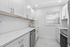 Sleek and modern kitchen with bright white cabinetry, elegant subway tile backsplash, and stainless steel appliances.