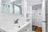 Elegant modern bathroom with sleek fixtures, large mirror, and ample storage space, featuring a glass shower enclosure.