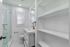 Bright and modern bathroom featuring sleek glass shower, elegant sink, and ample built-in shelving.