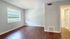 Bright and airy room with elegant hardwood flooring, large window inviting natural light, and smooth, modern walls.