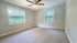 Bright and spacious bedroom with dual windows, modern ceiling fan, and soothing neutral tones.