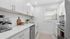 Bright and modern galley kitchen with sleek white cabinetry, stainless steel appliances, and a chic subway tile backsplash.
