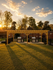 Charming outdoor space featuring a modern pergola with two sleek stainless-steel grills, set against a picturesque sunset backdrop.