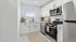 Modern white kitchen with stainless steel appliances and sleek cabinetry, illuminated by natural light.