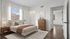 Bright, serene bedroom with modern wooden furnishings, soft textiles, and ample natural light from large window.